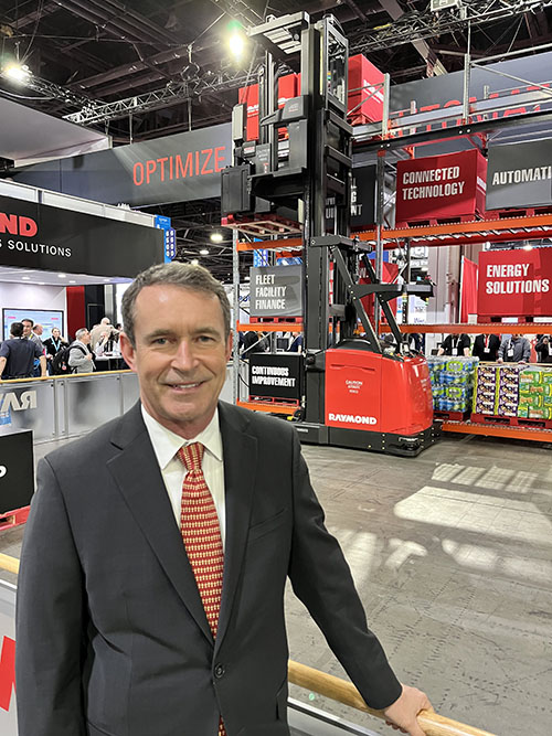雷蒙德公司总裁兼首席执行官迈克尔·菲尔德(Michael Field)，背景是该公司的一辆自动摆动伸展卡车。
